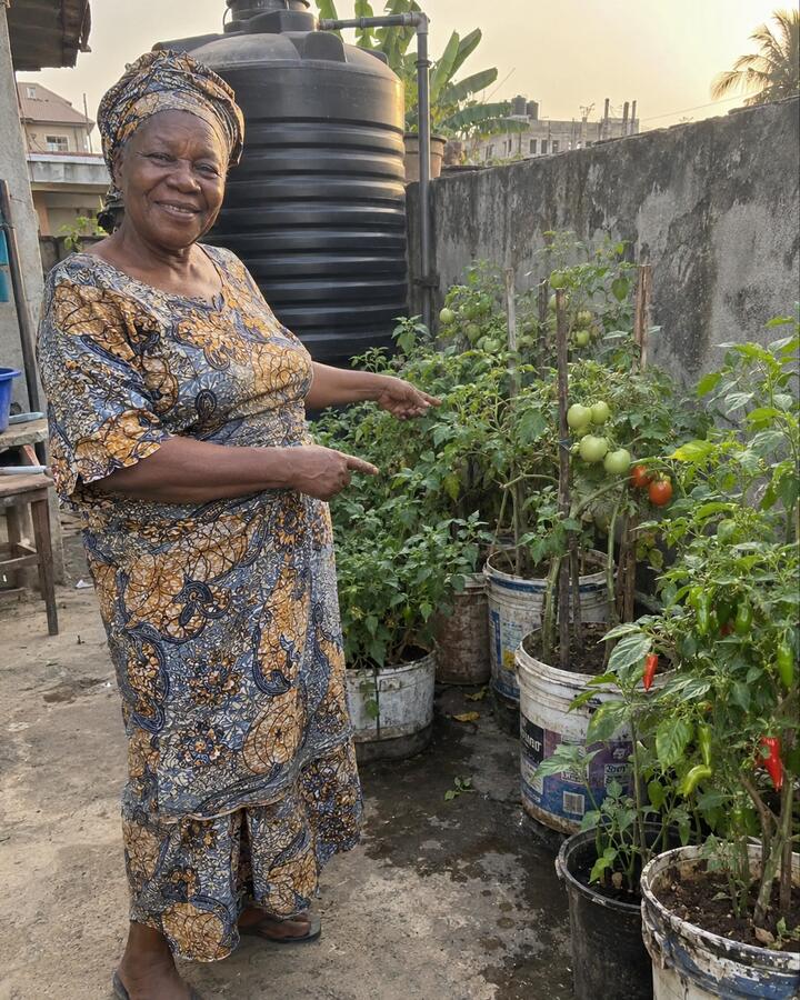 Mom in her garden in Lagos, pointing at her tomato plants
