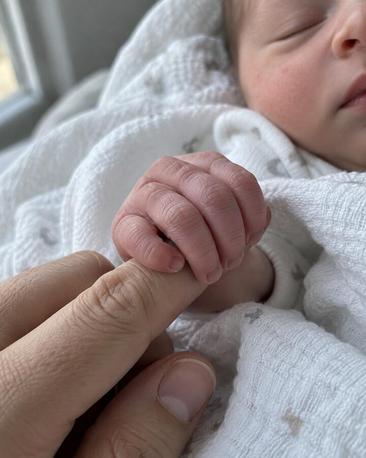 A newborn's hand holding a finger